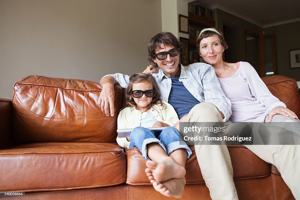 Smiling family on sofa wearing 3D glasses