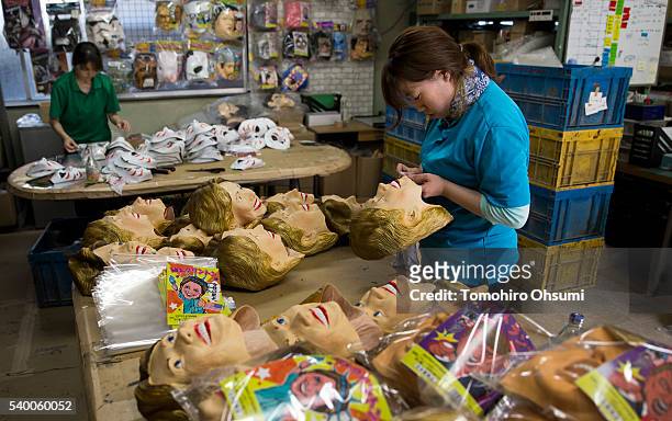 An employee inspects a rubber mask in the likeness of Democratic presidential candidate Hillary Clinton at the Ozawa Studios Inc. Factory on June 14,...