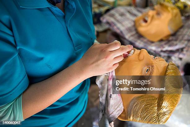 An employee inspects a rubber mask in the likeness of Republican presidential candidate Donald Trump at the Ozawa Studios Inc. Factory on June 14,...