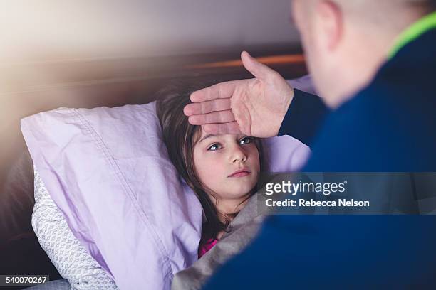 father checking daughter's forehead for fever - illness stock pictures, royalty-free photos & images