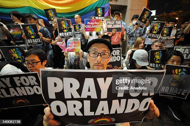 People pay tribute to victims of shooting at Pulse Nightclub in Orlando by holding banners and lighting candles, on June 14, 2016 at Shinjuku...