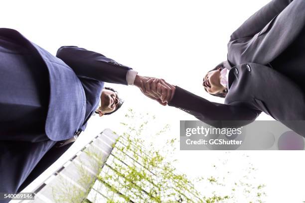 dois executivos de escritório a apertar as mãos sobre um acordo - japanese bussiness woman looking up imagens e fotografias de stock