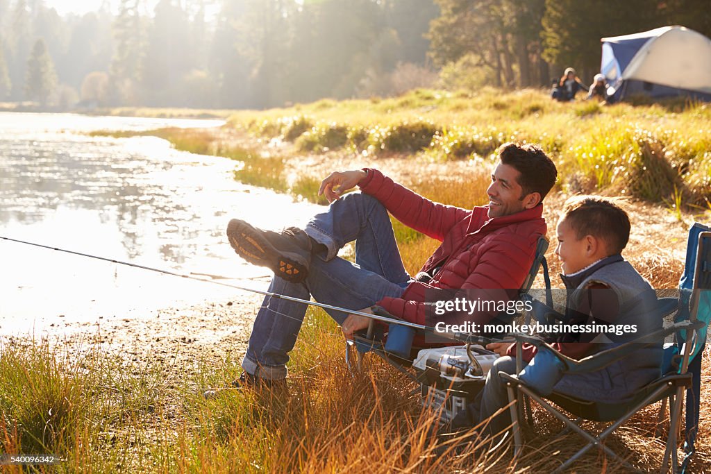 Father and son on a camping trip fishing by a lake