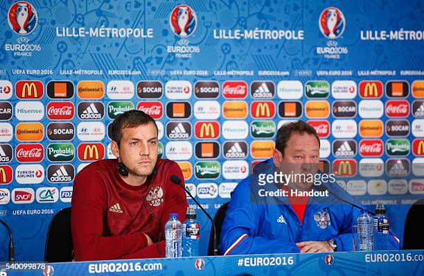 In this handout image provided by UEFA, Head Coach, Leonid Slutski of Russia talks to the media with Artem Dzyuba during the Russia Press Conference...