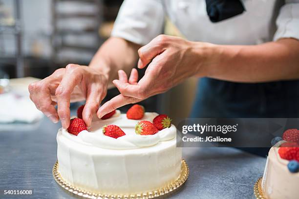 cake maker placing strawberries on a cake - strawberry and cream stock pictures, royalty-free photos & images