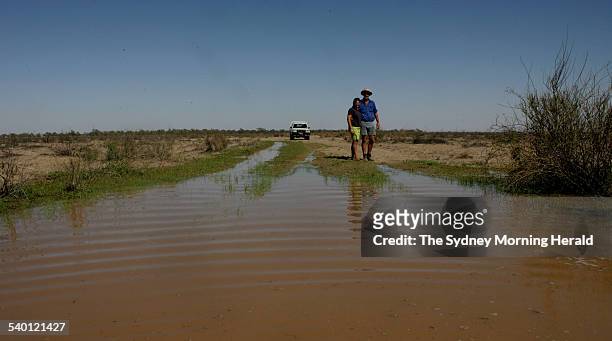 Bill and Lisa Ridge beside a flooded channel on their property, Tuon, near Enngonia, that receives water via the Tuen Creek feed by the Warrego...
