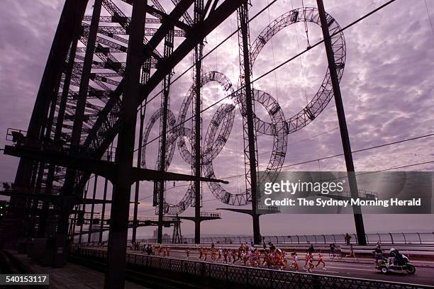 The women's marathon runners pass the Olympic rings suspended on the Sydney Harbour Bridge as they make their way from North Sydney to the Olympic...