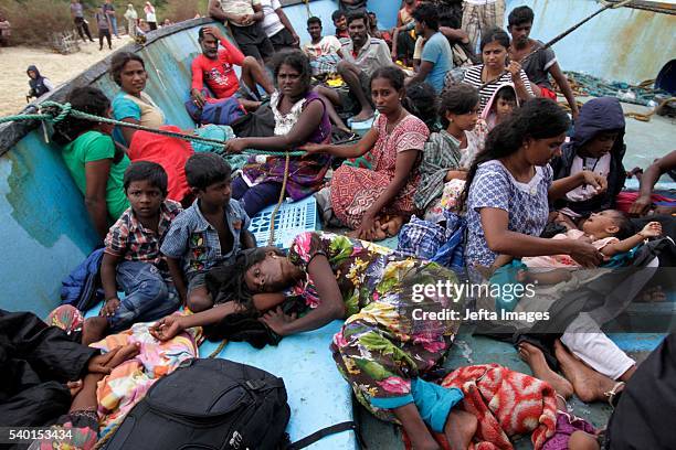 Migrants from Sri Lanka remain on their boat despite their vessel being washed ashore on the west coast of Lhoknga on June 14, 2016 in Aceh Besar,...