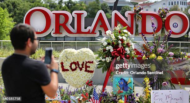 Jose Acevido Negron takes a photo with his iPhone as visitors continue to pay their respects at a makeshift memorial at Orlando Regional Medical...