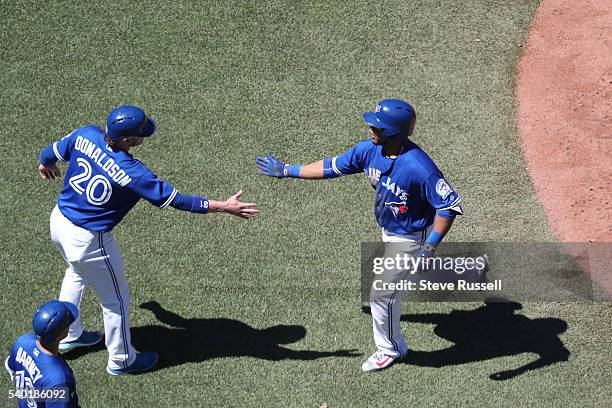 Josh Donaldson congratulates Edwin Encarnacion after he homers in the seventh inning as the Toronto Blue Jays play an afternoon game against the...