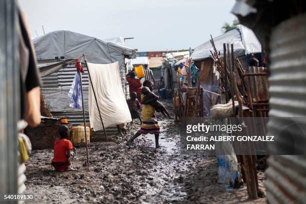 Child carries her young relative in the Protection of Civilians site in Malakal, on June 14, 2016. The rainy season started and made the living...