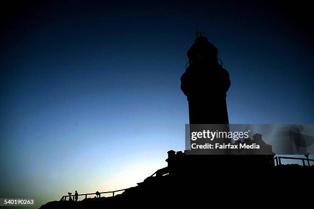 Tourists watch the sun set from cape byron lighthouse