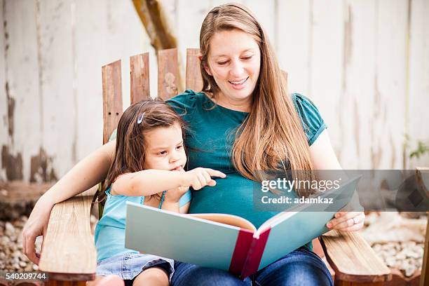 pregnant woman reading to daugther in backyard - read book outside young woman stock pictures, royalty-free photos & images