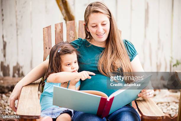 pregnant woman reading to daugther in backyard - read book outside young woman bildbanksfoton och bilder