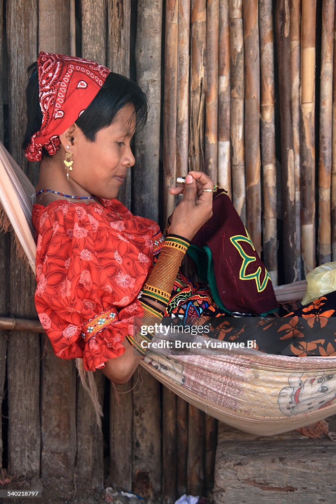 Kuna woman in traditional outfits making mola