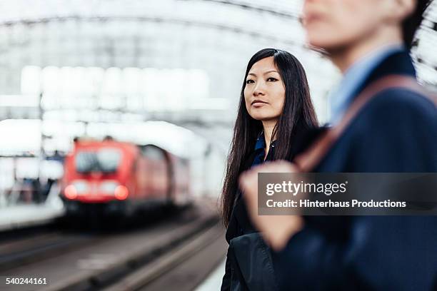 asian businesswoman waiting for her train - depot stock-fotos und bilder