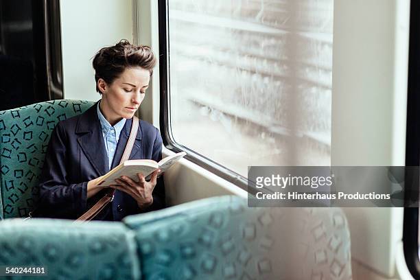 businesswoman reading book in train - reading stock-fotos und bilder
