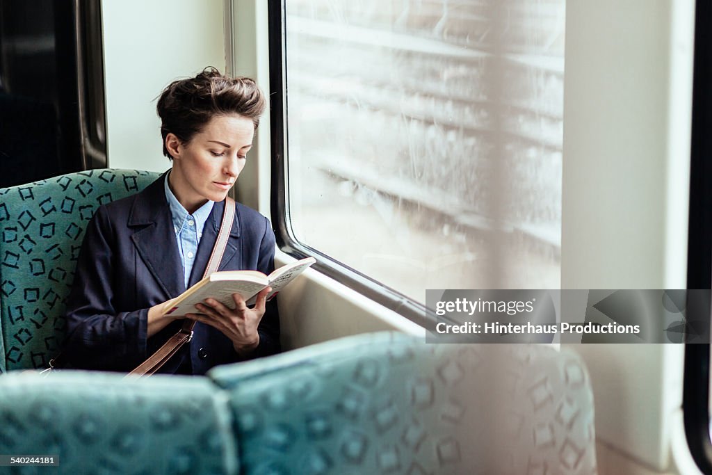 Businesswoman Reading Book In Train