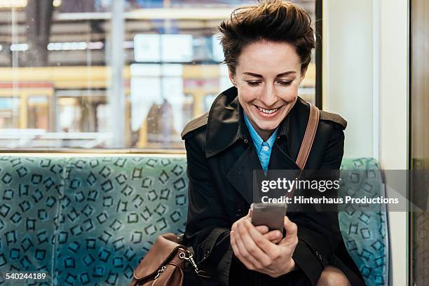 businesswoman with smart phone in commuter train - smile train stock pictures, royalty-free photos & images