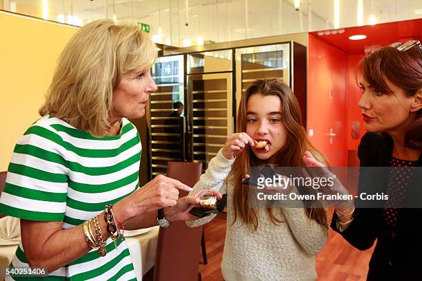 Dr. Jill Biden and her grand-daughter Natalie Biden try samples of food as they meet with students and staff during a visit to the Lycée Hôtelier...