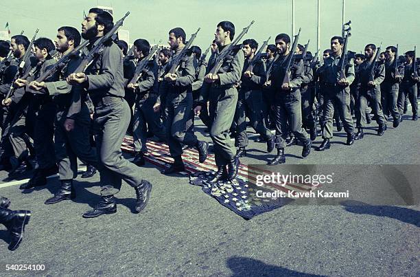 Members of the Iranian Revolutionary Guards march over a US flag spread on the tarmac of Azadi square, during a military parade on the third...