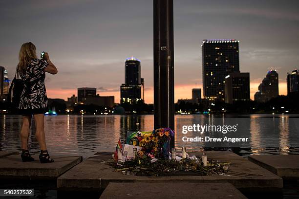 Woman takes a photo of the sunset next to a small memorial for the victims of the Pulse Nightclub shooting, at Lake Eola, June 14, 2016 in Orlando,...