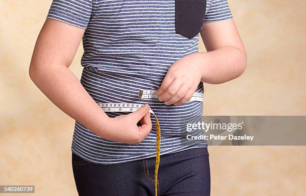 obese child measuring herself - holding a pair of pants stock pictures, royalty-free photos & images