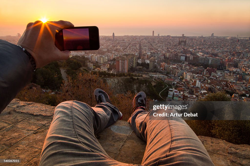 Man from pov taking pictures on Barcelona sunrise.