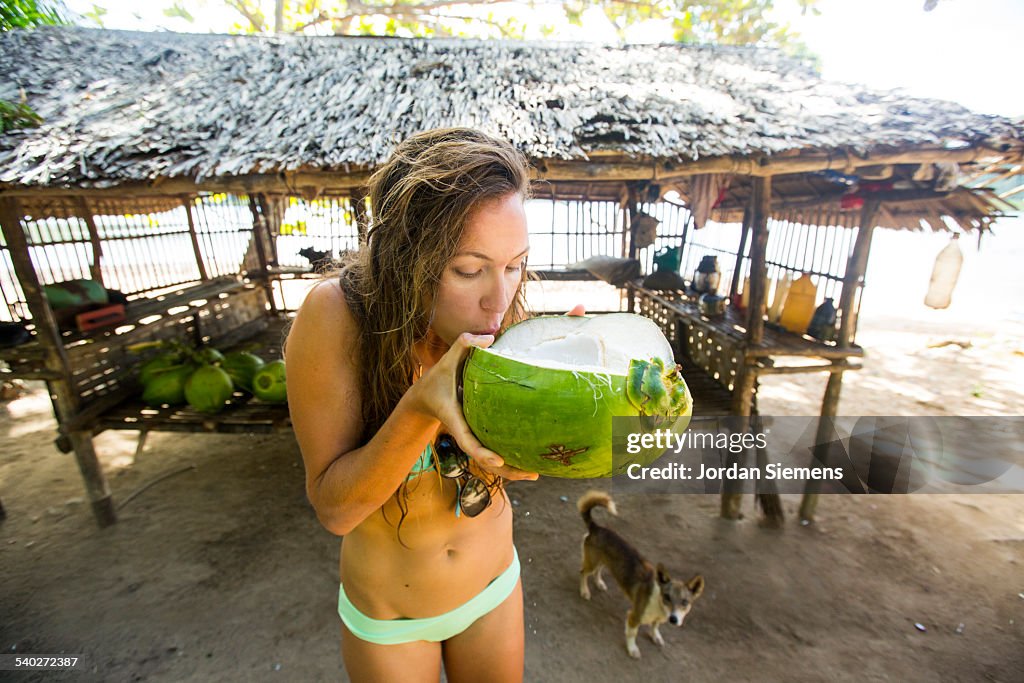 A woman drinking from a young fresh coconut.