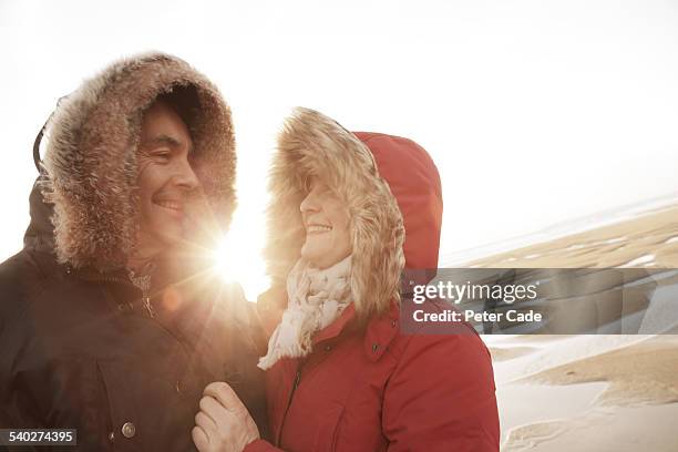 couple on beach wearing winter coats and hats . - mature couple winter outdoors stockfoto's en -beelden