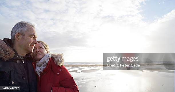couple on beach, woman looking at man , winter - mature couple winter outdoors stock pictures, royalty-free photos & images