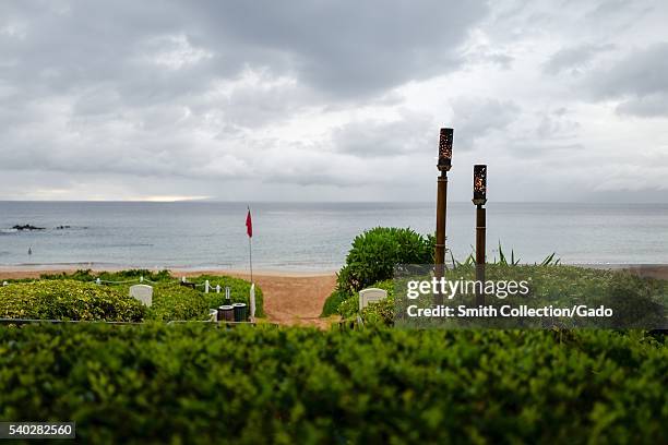 Rainy and overcast day at Wailea Beach, viewed from the terrace of the Four Seasons Resort Maui at Wailea, with a red flag indicating unsafe ocean...