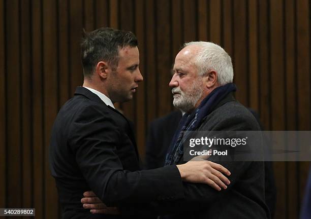 Oscar Pistorius reaches out to his father Henke Pistorius during the third day of Oscar's hearing for a resentence at Pretoria High Court on June 15,...