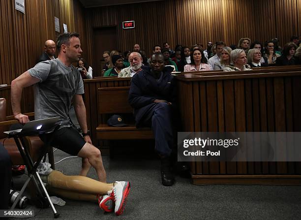 Oscar Pistorius takes off his legs as he prepares to walk across the courtroom without his prosthetic legs during the third day of Oscar's hearing...