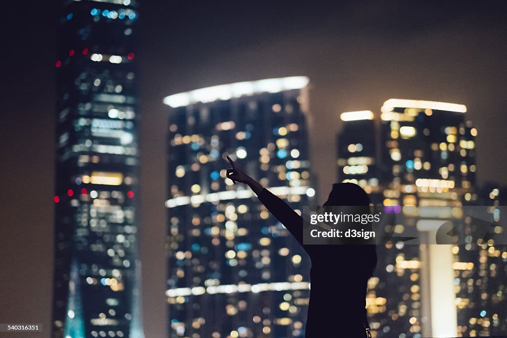 Silhouette of woman pointing to the city skyline