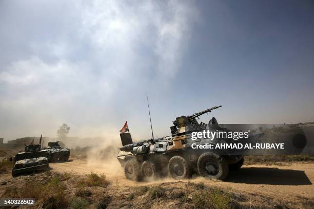 Iraqi government forces drive their armoured vehicles during an operation, backed by air support from the US-led coalition, in Fallujah's southern...