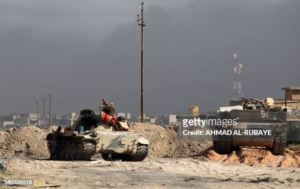 Iraqi government forces hold a position with their tanks during an operation, backed by air support from the US-led coalition, in Fallujah's southern...
