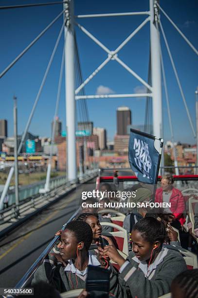 South African students from Chief Albert Luthuli Primary and High School in Daveyton take a ride on a bus tour in Johannesburg on June 15 on the eve...