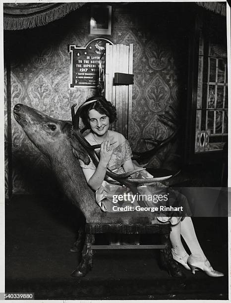 Gertrude Olmstead, actress from the 1920's seated on a chair made from the head and body of an elk. Undated photograph.