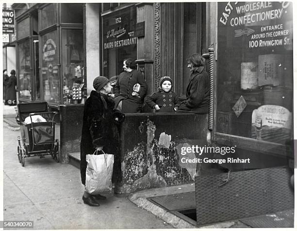 New York, NY: Coming home from market, a resident of the slum section in New York stops to chit chat with one of her neighbors. Undated photograph.