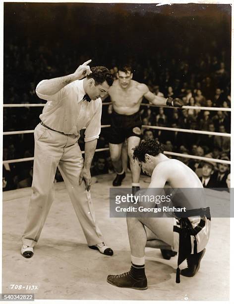 Jack Dempsey is shown in the role of referee as Max Baer kneels on the canvas in the ring, being counted on a knockdown. Undated photograph.