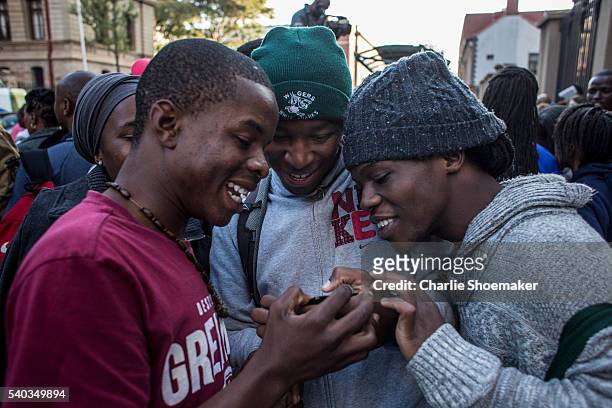 Group of boys look at photos on their phone that they took of Oscar Pistorius leaving the North Gauteng High Court on June 15, 2016 in Pretoria,...
