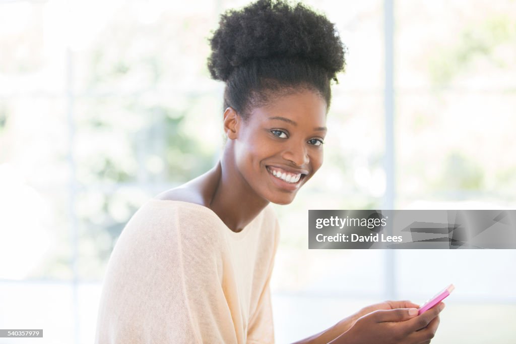 Smiling woman using mobile phone indoors