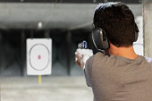 man firing usp pistol at target in indoor shooting range