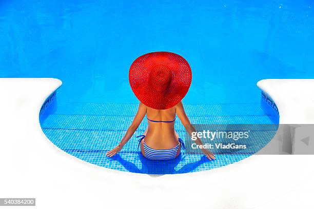 woman relaxing in a resort swimming pool - pink hat stock pictures, royalty-free photos & images