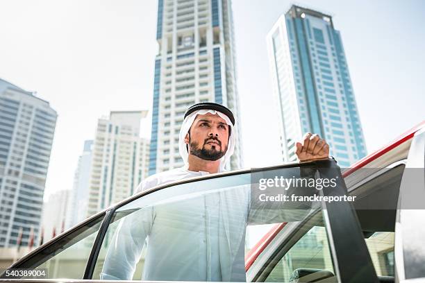 arabo sceicco in piedi fuori del taxi - dubai taxi foto e immagini stock
