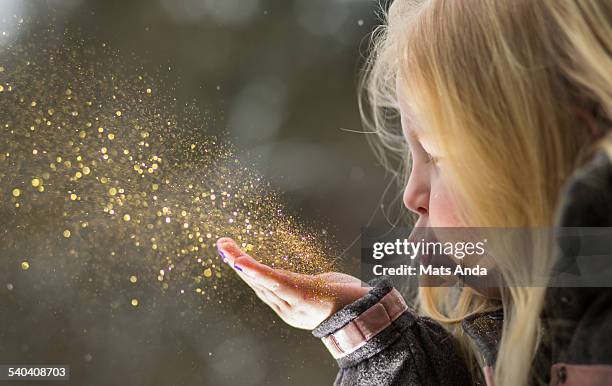 young girl blows glitter into the air - blowing dust stock pictures, royalty-free photos & images