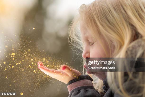 young girl blows glitter into the air - gold nail polish stock-fotos und bilder