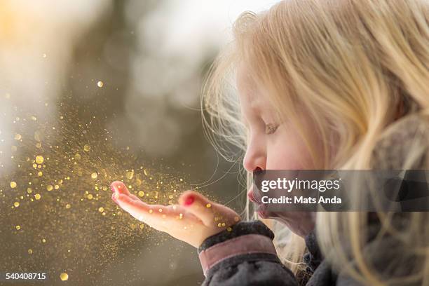 young girl blows glitter into the air - sparkle children stock pictures, royalty-free photos & images