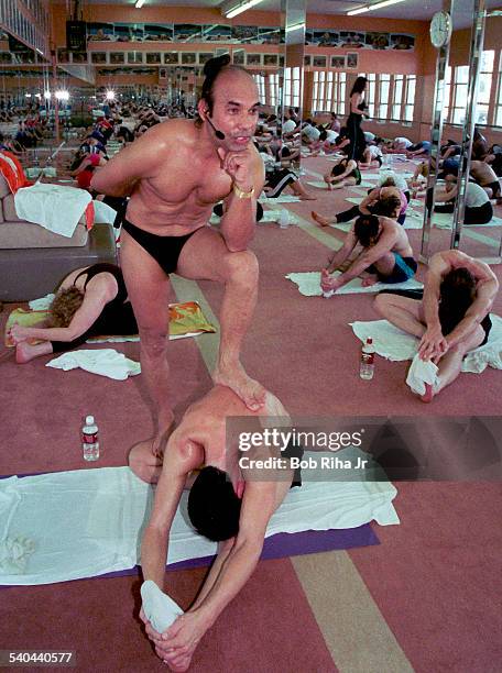 Indian Yoga guru Bikram Choudhury instructs his yoga class as he stands on the back of student Michael Rimokh during a workout in heated room,...